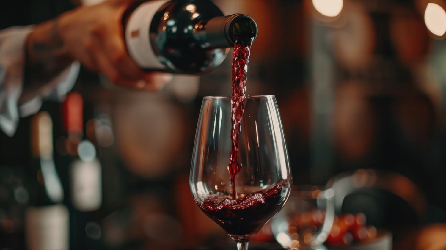 Verter vino tinto en un vaso con un fondo borroso del barril